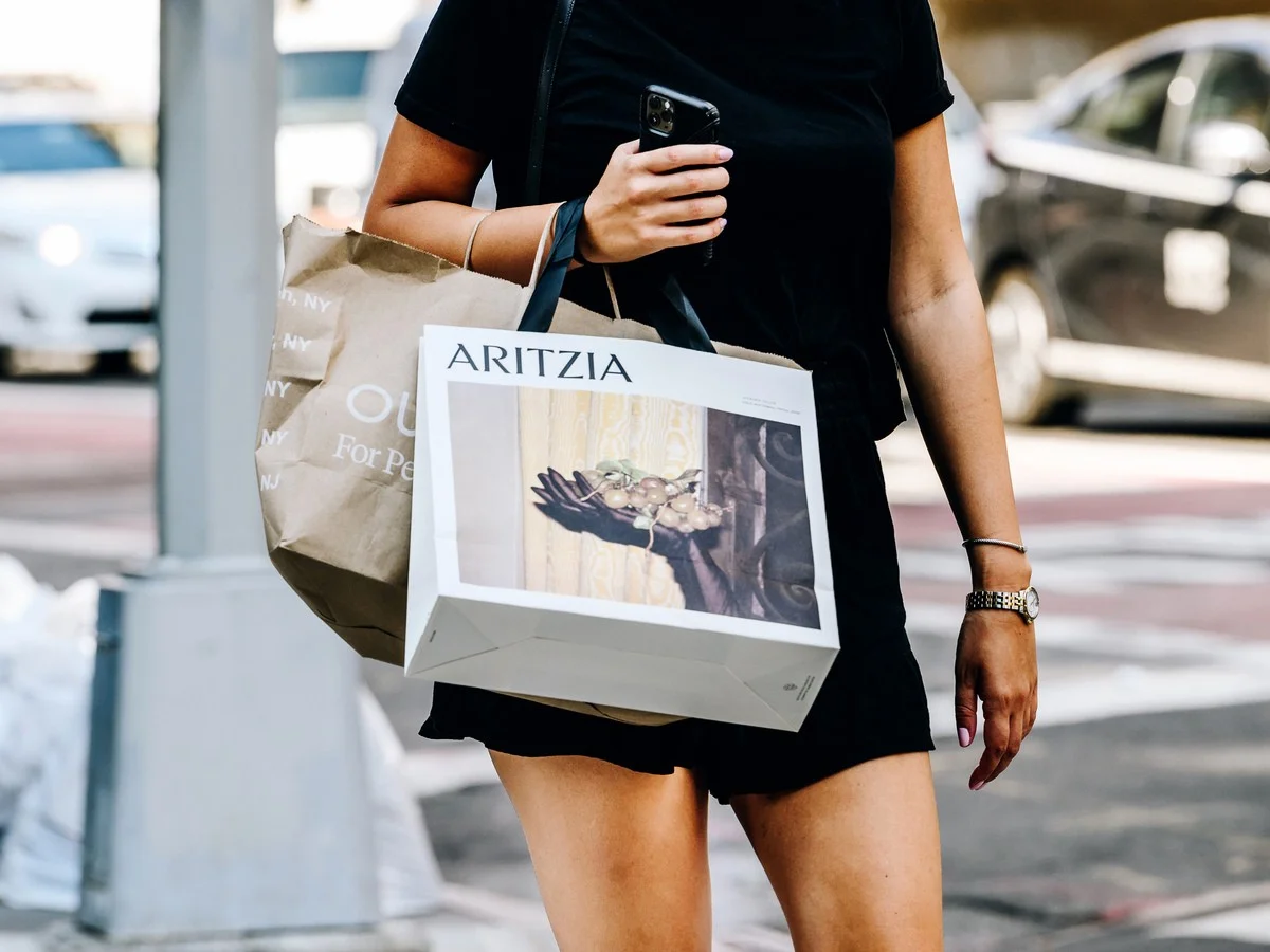 A pedestrian carries an Aritzia Inc. shopping bag while crossing a street in the Soho neighbourhood of New York.